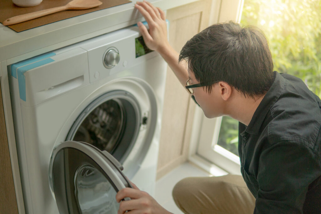 Technician installing heat pump washer dryer combo unit in residential home.