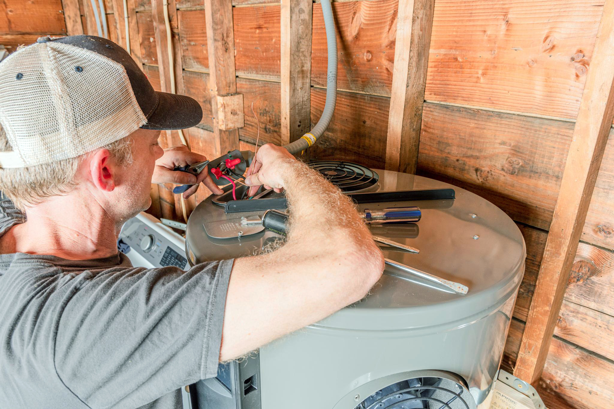 Installing a heat pump water heater in an unfinished residential garage.